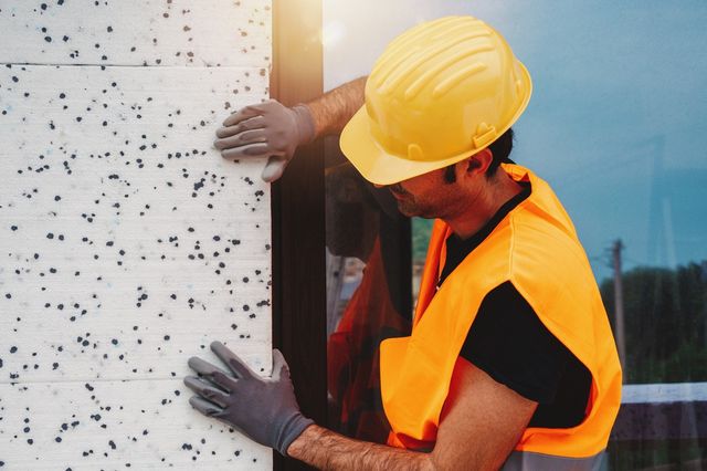 trabajador fijando placa de revestimiento de pared blanca con manchas negras