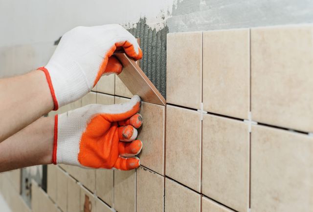 trabajador colocando baldosas de cerámica beige en una pared